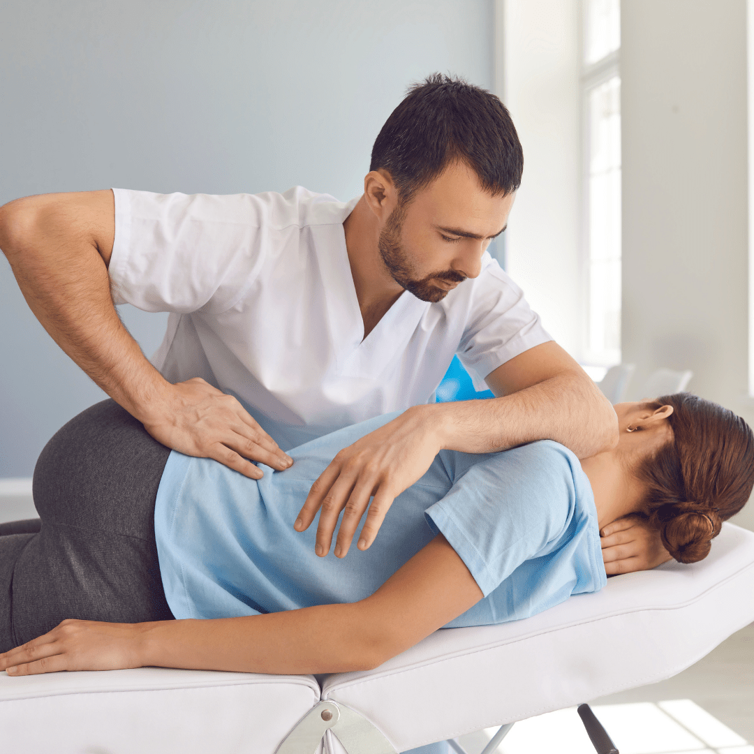 A chiropractor adjusts a woman's hip.