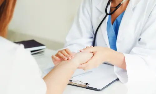 A woman doctor examining and counting the patient's pulse with her hands.